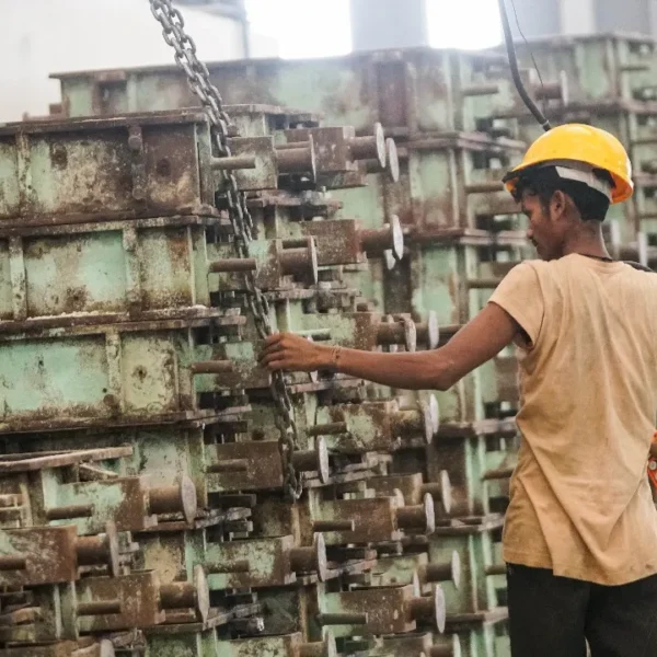 Worker operating industrial machinery on a foundry floor