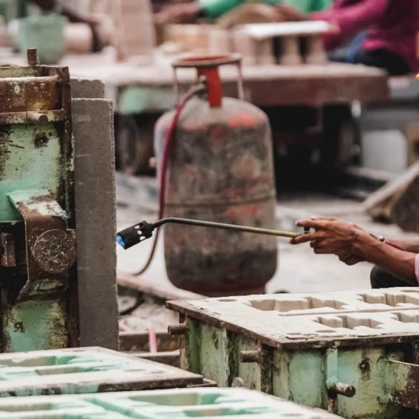 Foundry worker applying heat to a casting mould