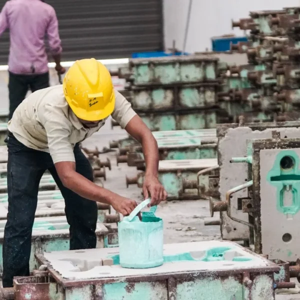 Worker applying protective coating to industrial sand-casting moulds
