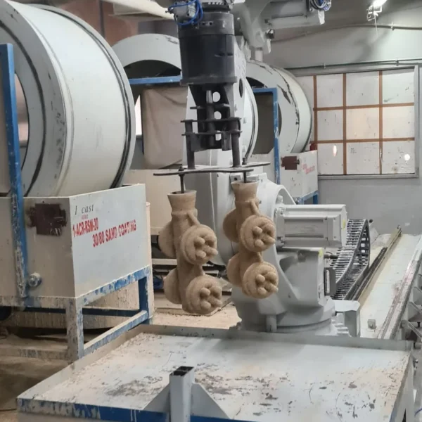Robotic arm dipping wax pattern clusters at an investment casting shell coating station